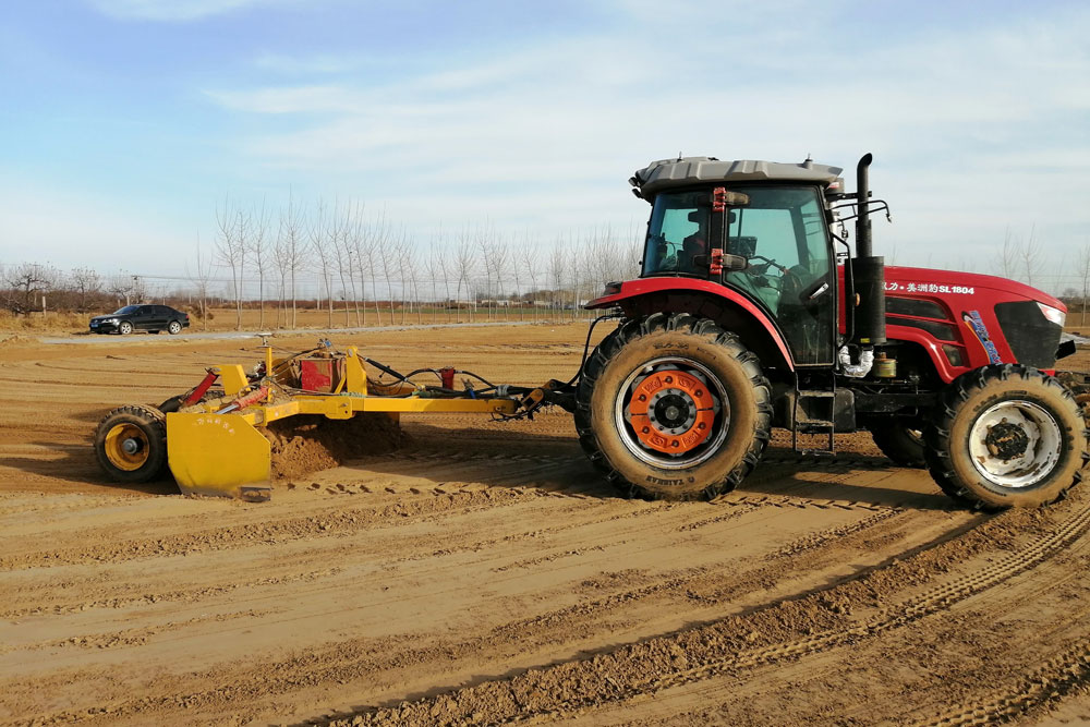 Sárga terepegyengető nyesőládát vontató traktor